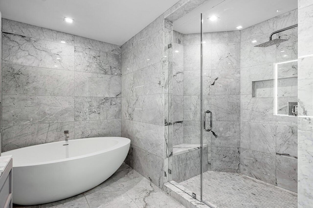 bathroom featuring tile walls, a freestanding tub, a shower stall, and marble finish floor