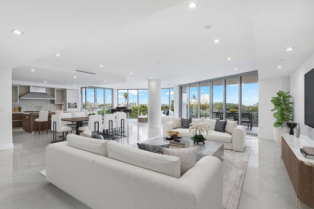 living room with a wall of windows, recessed lighting, marble finish floor, and plenty of natural light