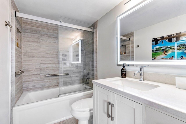 full bathroom featuring toilet, shower / bath combination with glass door, and vanity