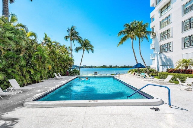 view of swimming pool featuring a water view and a patio area