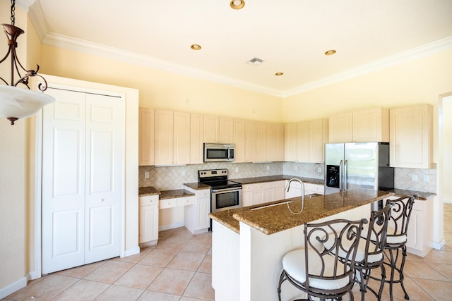 kitchen featuring a center island with sink, visible vents, a sink, stainless steel appliances, and a kitchen bar