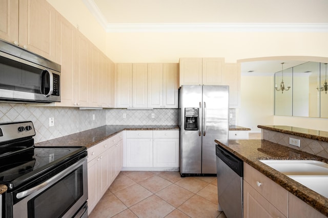 kitchen with light tile patterned floors, stainless steel appliances, backsplash, and ornamental molding