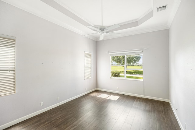 empty room featuring visible vents, ornamental molding, dark wood finished floors, baseboards, and a raised ceiling