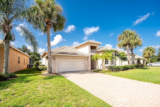 mediterranean / spanish-style home with an attached garage, stucco siding, a front lawn, a tile roof, and decorative driveway