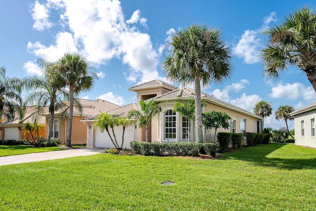 mediterranean / spanish-style home featuring an attached garage, a front lawn, a tiled roof, stucco siding, and driveway