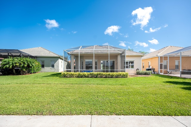 back of property with a lanai, a yard, a tile roof, and stucco siding