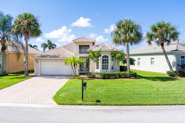 mediterranean / spanish-style house with a tiled roof, an attached garage, driveway, and a front yard