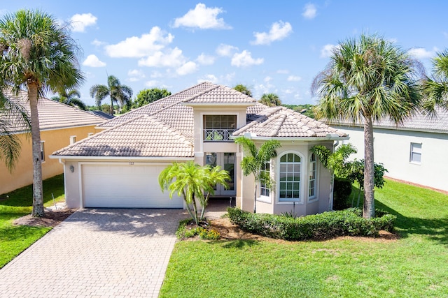 mediterranean / spanish-style home featuring a front yard, decorative driveway, a tile roof, and stucco siding