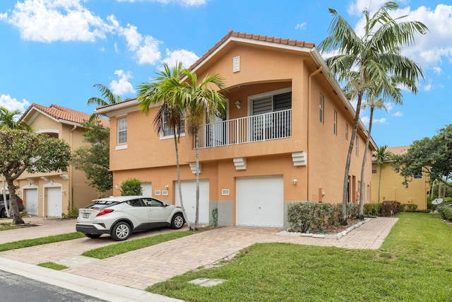 view of front of home featuring a garage, a balcony, and a front yard