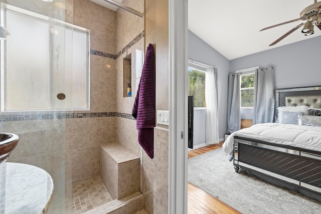 interior space with ceiling fan, lofted ceiling, hardwood / wood-style floors, and a tile shower