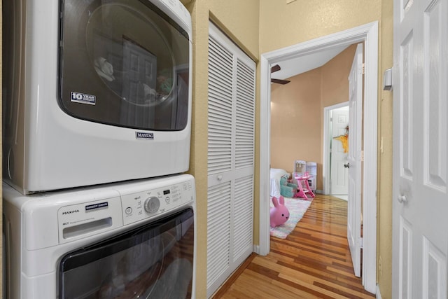 clothes washing area with hardwood / wood-style floors and stacked washing maching and dryer