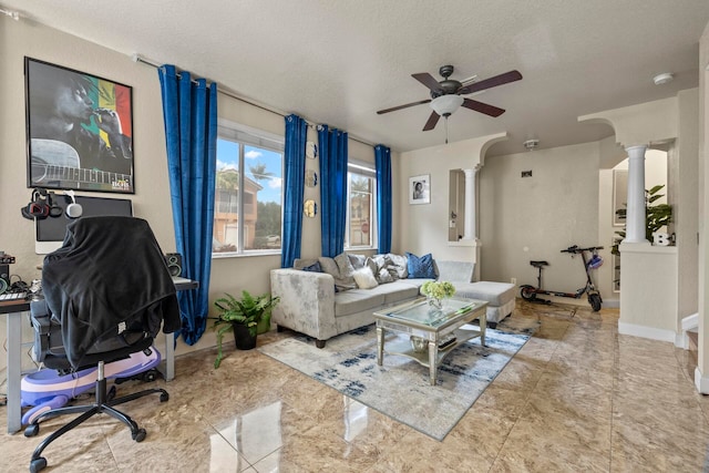 tiled living room featuring a textured ceiling, ceiling fan, and ornate columns