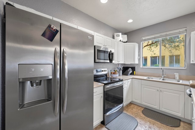 kitchen featuring appliances with stainless steel finishes, white cabinetry, light tile patterned floors, and sink