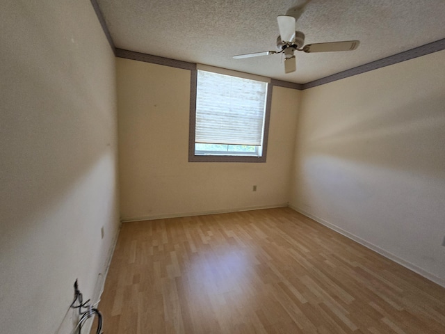 empty room with a ceiling fan, light wood-type flooring, and a textured ceiling