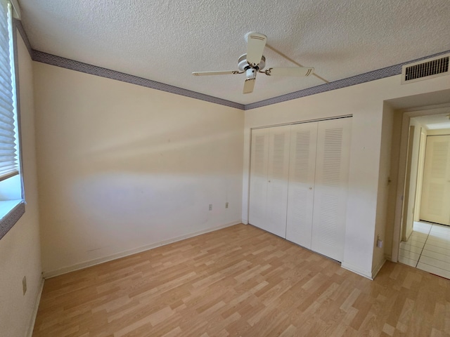 unfurnished bedroom with light hardwood / wood-style flooring, ornamental molding, a textured ceiling, a closet, and ceiling fan