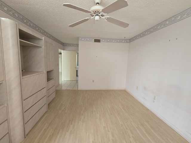 interior space with a textured ceiling, baseboards, visible vents, and light wood-style floors