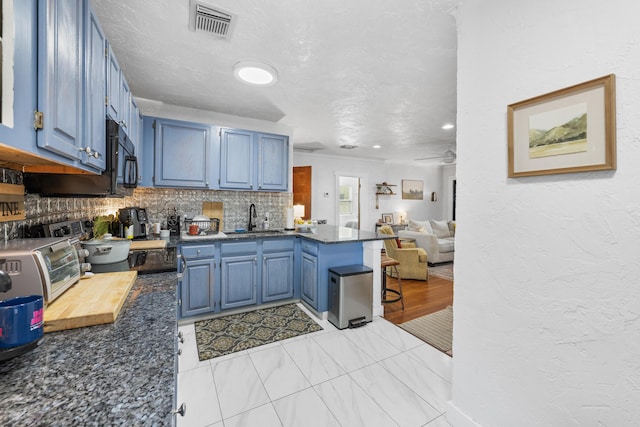 kitchen featuring sink, a breakfast bar, tasteful backsplash, blue cabinets, and kitchen peninsula