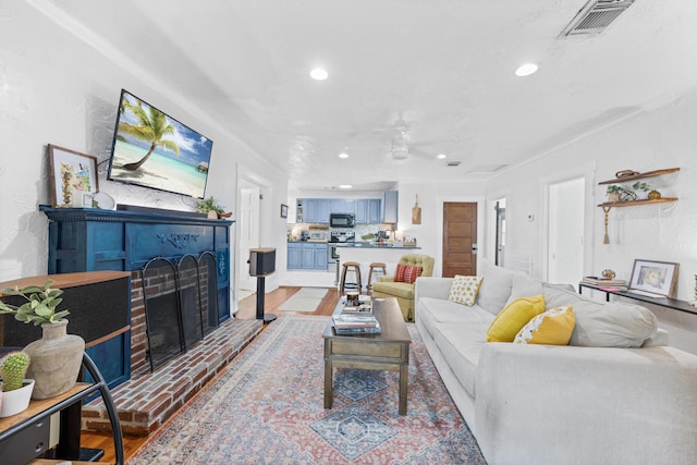 living room with a brick fireplace, light hardwood / wood-style flooring, and ceiling fan