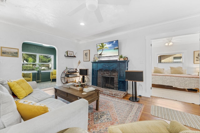 living room featuring ornamental molding, a brick fireplace, ceiling fan, and light hardwood / wood-style floors