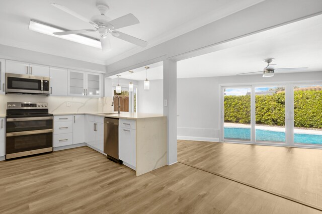 kitchen with sink, light wood-type flooring, white cabinetry, stainless steel appliances, and decorative backsplash