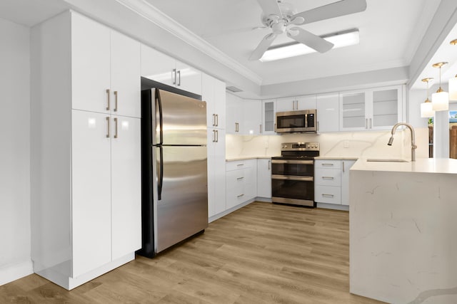 kitchen featuring appliances with stainless steel finishes, sink, white cabinetry, light hardwood / wood-style floors, and pendant lighting