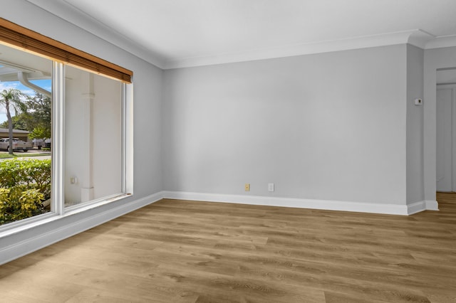 empty room with a healthy amount of sunlight, ornamental molding, and light wood-type flooring