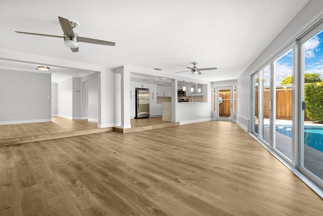 unfurnished living room with hardwood / wood-style floors, sink, and ceiling fan