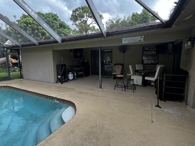 view of pool featuring glass enclosure and a patio