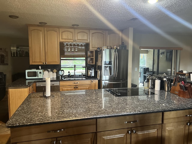 kitchen featuring sink, appliances with stainless steel finishes, a textured ceiling, and dark stone counters