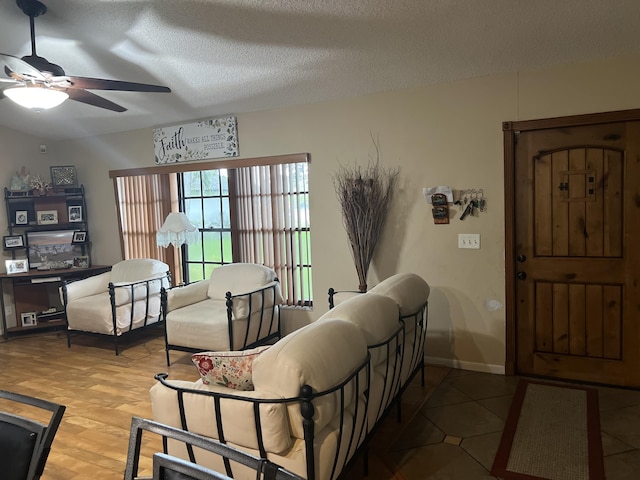 living room with ceiling fan, a textured ceiling, and light hardwood / wood-style floors