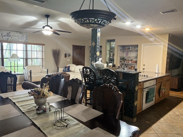 dining space featuring a textured ceiling, ceiling fan, and tile patterned floors