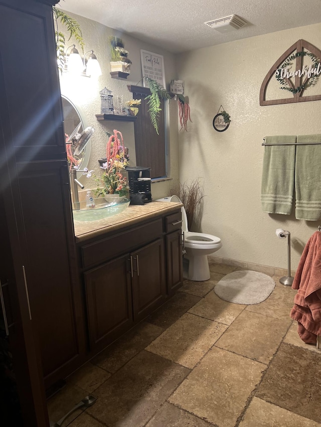 bathroom featuring a textured ceiling, toilet, tile patterned flooring, and vanity