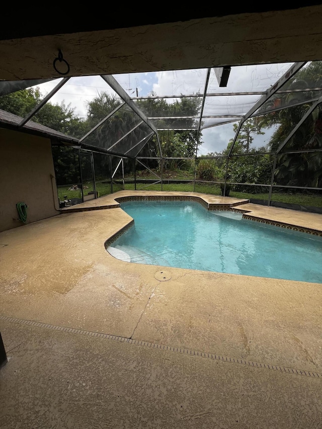 view of swimming pool with a patio and a lanai