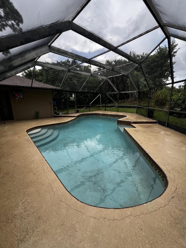 view of pool featuring glass enclosure and a patio