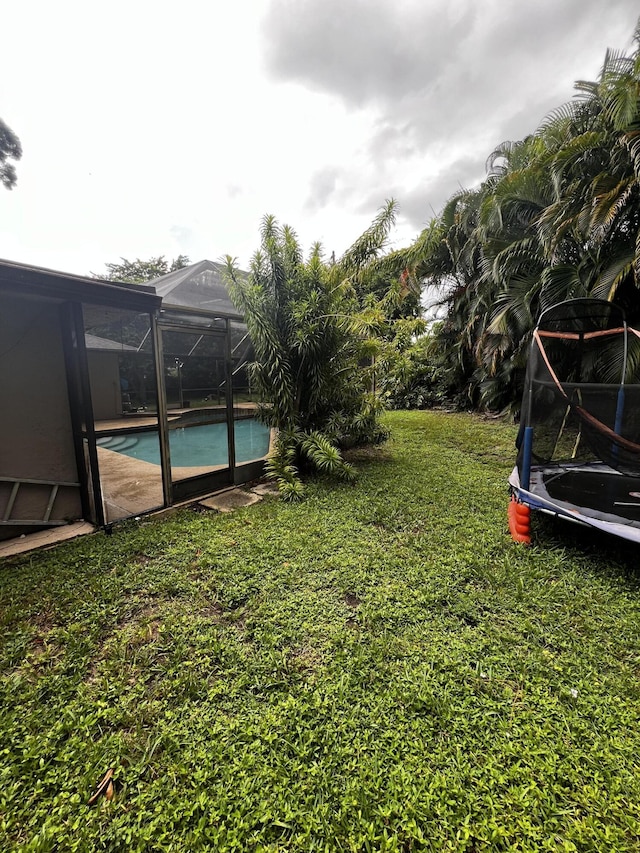 view of yard featuring a lanai and a trampoline