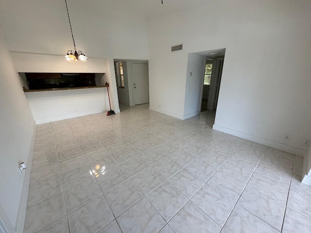 unfurnished living room featuring a high ceiling, visible vents, and baseboards