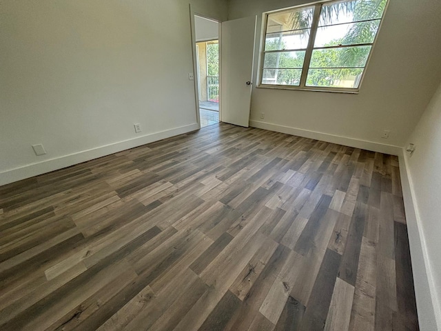 unfurnished room featuring baseboards and dark wood-type flooring