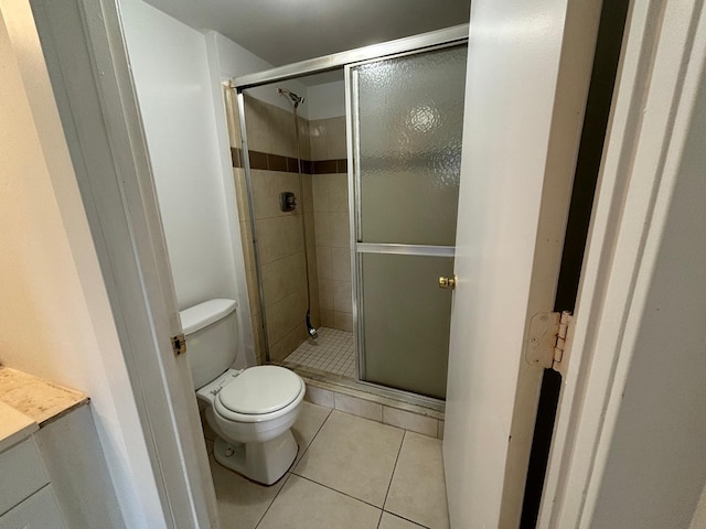 bathroom featuring toilet, tile patterned flooring, vanity, and a shower stall