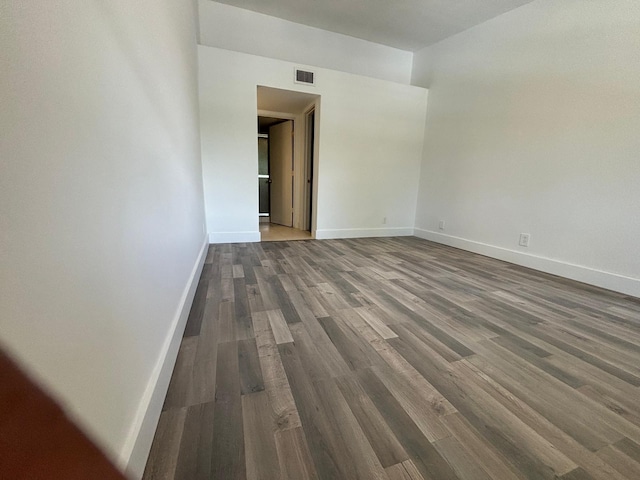 spare room featuring dark wood-style floors, visible vents, and baseboards