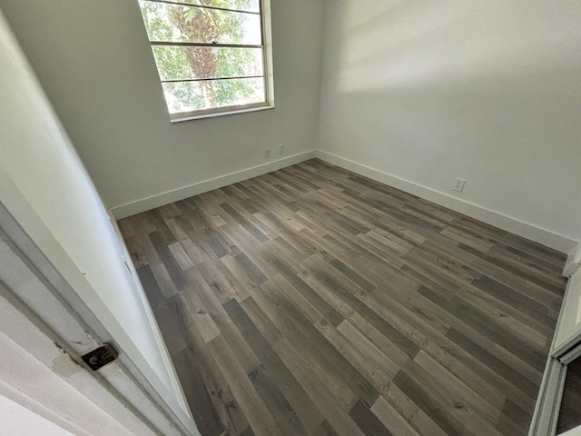 unfurnished room featuring dark wood-type flooring and baseboards