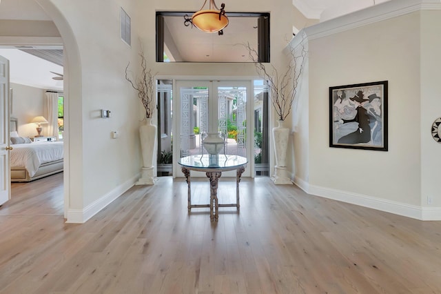 interior space featuring light wood-type flooring, crown molding, and a high ceiling