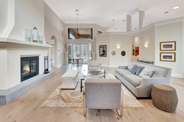 living room with crown molding, a high ceiling, and light hardwood / wood-style flooring