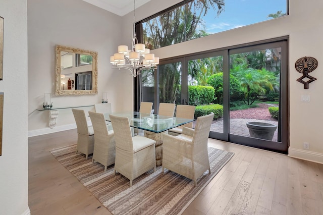 dining area featuring hardwood / wood-style flooring, a high ceiling, a notable chandelier, and crown molding