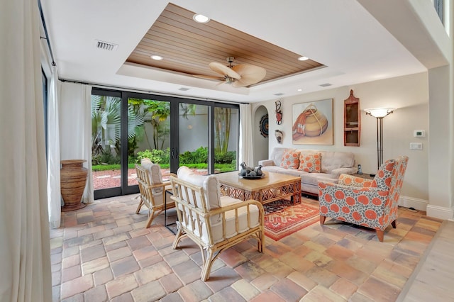 tiled living room with a tray ceiling, ceiling fan, french doors, and wood ceiling