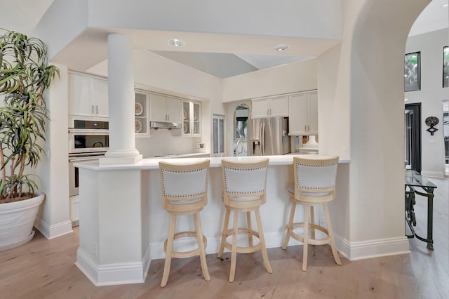 kitchen with sink, light wood-type flooring, white cabinetry, stainless steel appliances, and kitchen peninsula