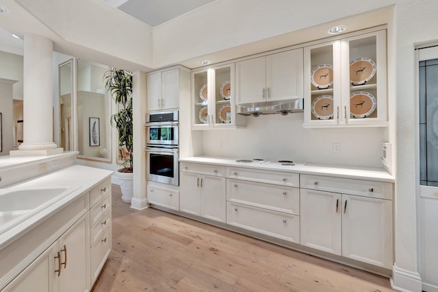 kitchen with double oven, white electric cooktop, light hardwood / wood-style floors, white cabinetry, and decorative columns