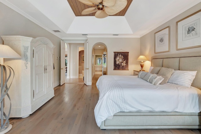 bedroom with ceiling fan, a raised ceiling, crown molding, and wood-type flooring