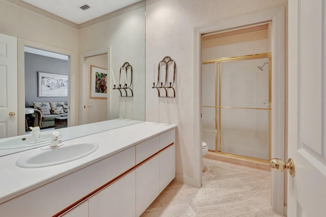 bathroom with crown molding, toilet, vanity, and a shower with shower door