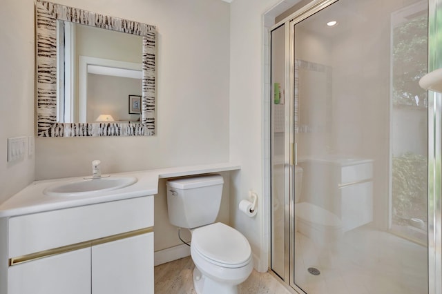 bathroom featuring hardwood / wood-style flooring, toilet, a shower with door, and vanity