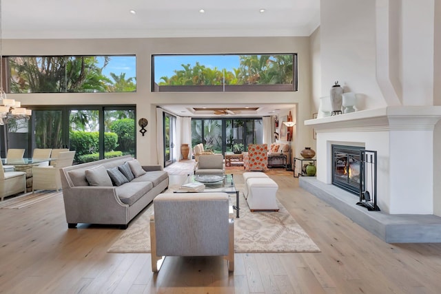 living room featuring light wood-type flooring, crown molding, and a high ceiling